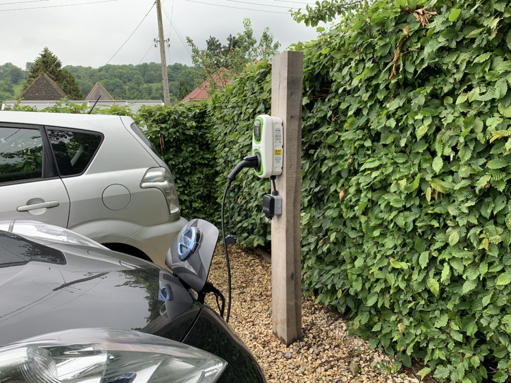 A photo of the oak post on our driveway, with the Rolec charging point on it and the cable running to our LEAF as it charges.