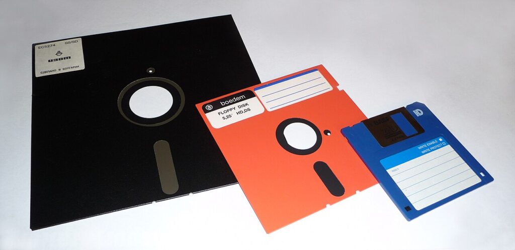 A photo of an 8-inch floppy disk, an orange 5.25-inch floppy disk and a 3.5-inch floppy disk.